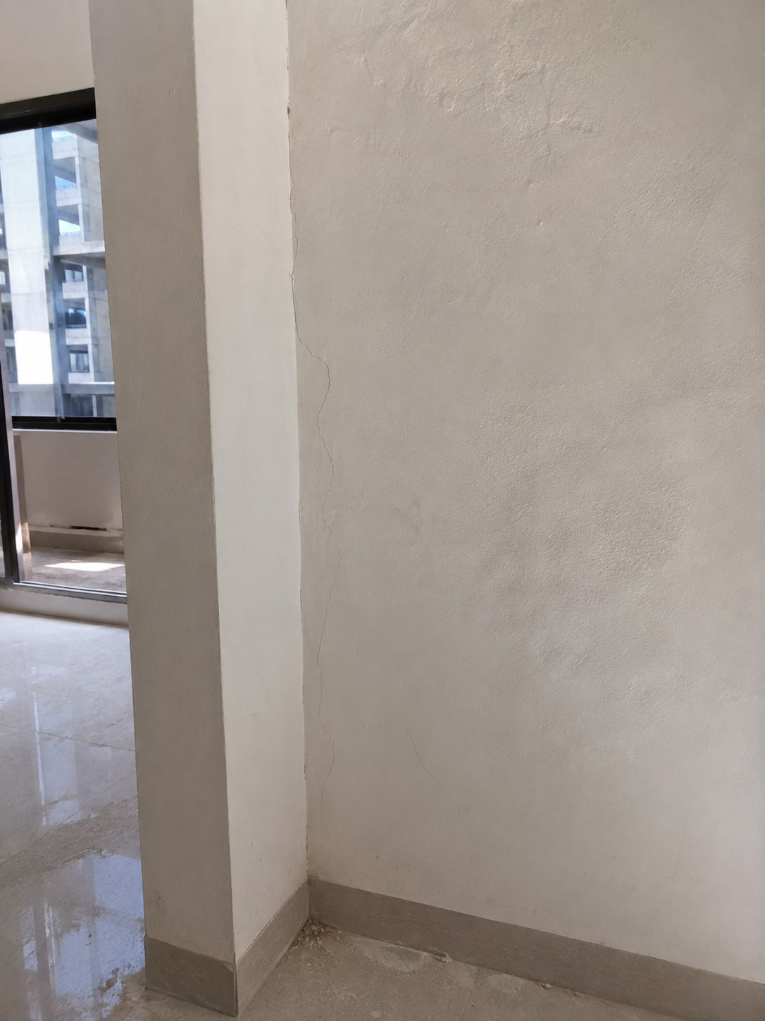 Fine crack running down an interior wall beside a column edge