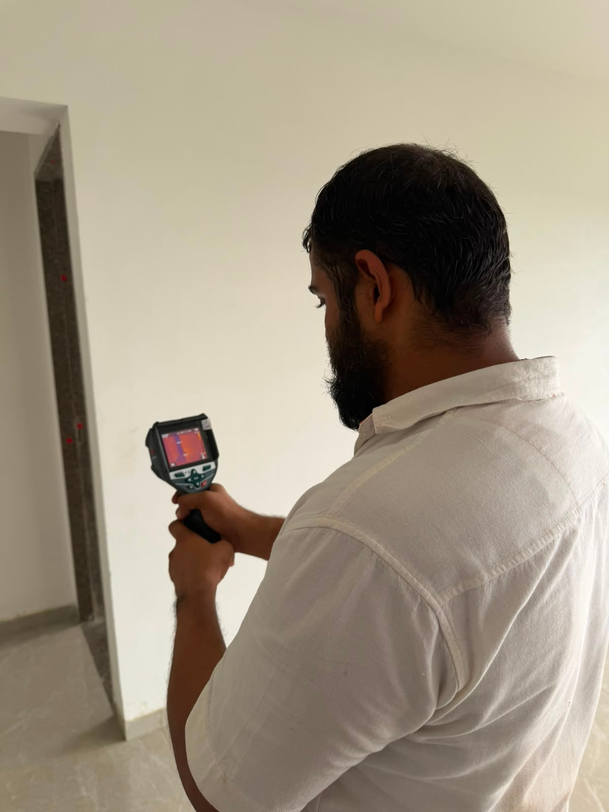 Inspector using a thermal camera on an accessible wall during a home inspection