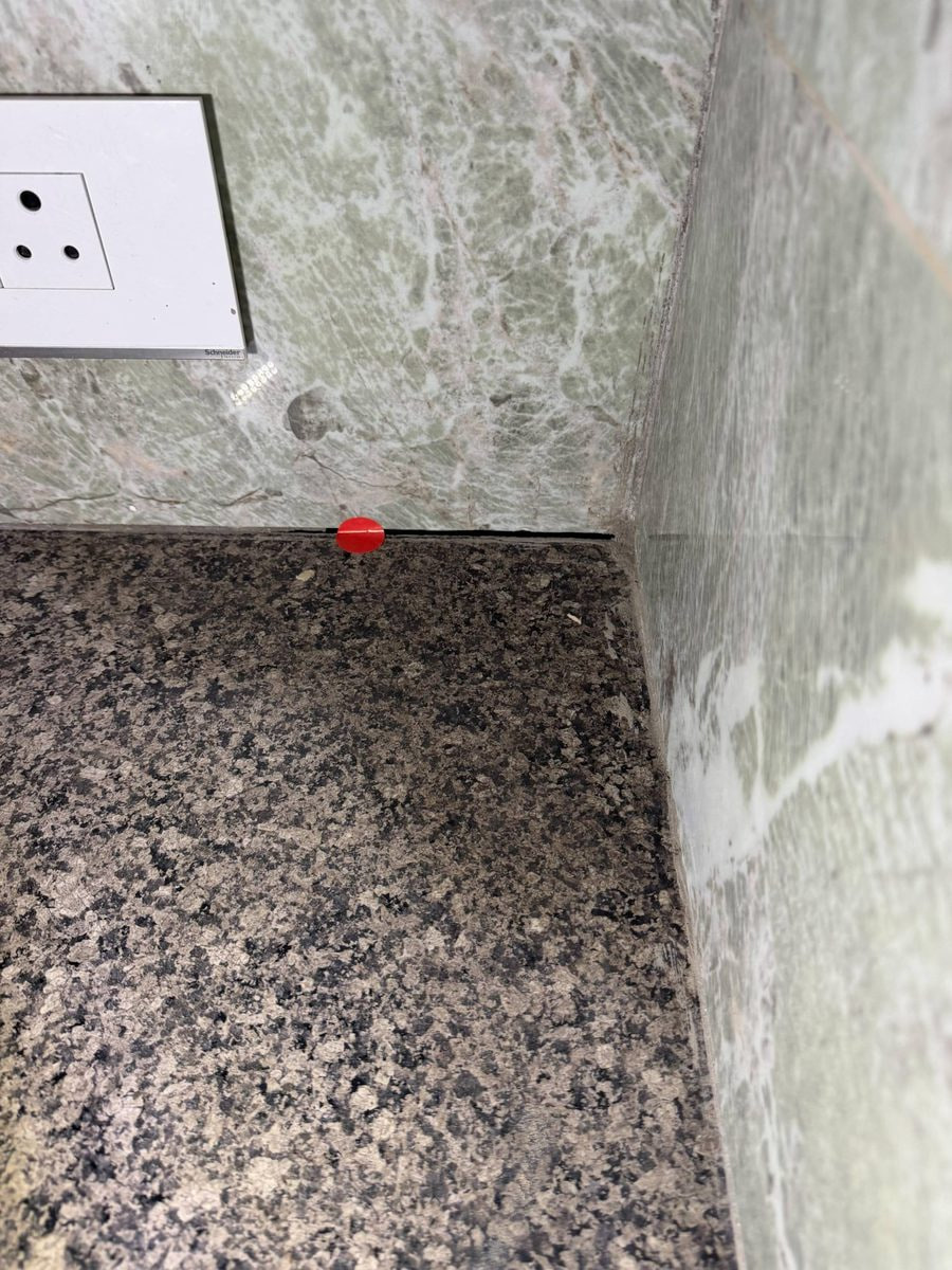 Red marker beside an incompletely grouted granite joint in a washroom